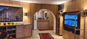 a living room with a tv and an archway at Hotel Alpenhof in Bad Tölz