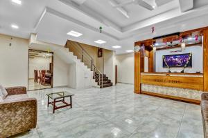 vestíbulo con sofá, TV y escaleras en Hotel Sai Sparsh, en Shirdi