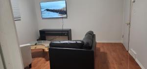 a black leather couch in a living room with a television at ChessKings Guest House - Unit 1 in Winnipeg