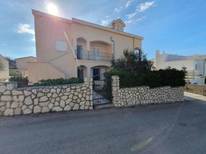 a house with a stone wall and a stone fence at Olive garden Pag in Pag