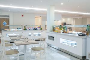 a restaurant with white counters and tables and chairs at Hotel Nerja Club Spa by Dorobe in Nerja