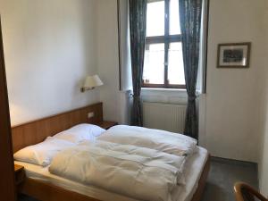 Bett in einem Schlafzimmer mit Fenster in der Unterkunft Gasthaus Klosterhof 