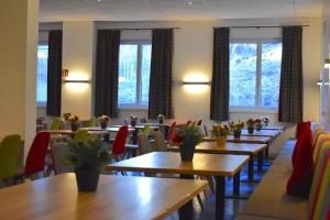 een restaurant met houten tafels, stoelen en ramen bij Sporthotel Zederhaus in Zederhaus