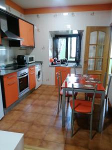 a kitchen with orange cabinets and a table with chairs at NIDO in Ribadeo