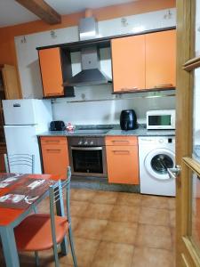 a kitchen with orange cabinets and a table and a stove at NIDO in Ribadeo