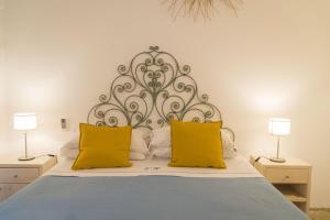 a bedroom with a bed with two yellow pillows at Villa Romasi in Leuca