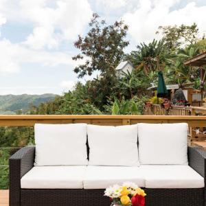 a white couch on a deck with mountains in the background at Villa Vacacional en Puerto Rico para parejas in Villalba