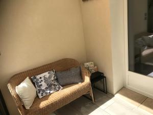 a wicker couch with pillows on it in a room at Maisonnette cosy à Châtillon-Coligny in Châtillon-Coligny