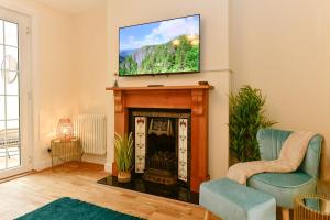 a living room with a fireplace with a television above it at Just Stay Wales - Castle Square Cottage, Mumbles in Oystermouth