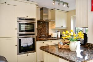 une cuisine avec des placards blancs et un vase de fleurs sur un comptoir dans l'établissement Just Stay Wales - Castle Square Cottage, Mumbles, à Oystermouth