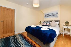 a bedroom with a large bed with a blue blanket at Just Stay Wales - Castle Square Cottage, Mumbles in Oystermouth