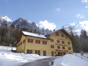 un bâtiment dans la neige avec des montagnes en arrière-plan dans l'établissement Garnì Sella Cipriani, à Borgo