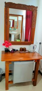 a wooden dressing table with a mirror and flowers on it at Dream Palace Family Guest House Mirissa in Mirissa