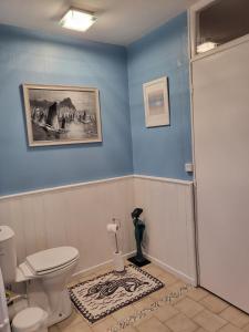 a bathroom with a toilet and a blue wall at Chambre d'Hote Woody in Chef-Boutonne