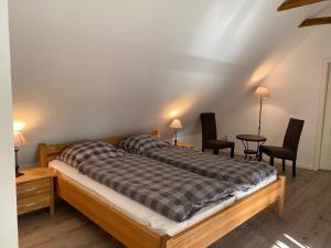 Schlafzimmer mit einem Bett mit 2 Stühlen und einem Tisch in der Unterkunft Cottage - Artland's Home - Landhaus für Familien und Gruppen in Badbergen