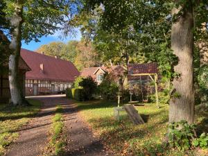 una casa con un árbol y un banco en el césped en Cottage - Artland's Home - Landhaus für Familien und Gruppen en Badbergen