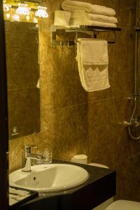ein Badezimmer mit einem Waschbecken, einem Spiegel und Handtüchern in der Unterkunft TRA LINH HOTEL in Hữu Lũng