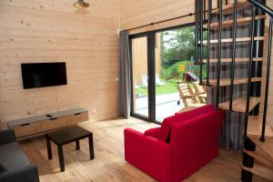 a living room with a red couch and a tv at Kapitanka Apartamenty in Okuninka