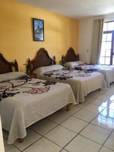 a room with three beds in a room at HOTEL CAMELINAS AREA BLANCA in Pátzcuaro