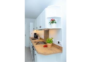 a kitchen with white cabinets and a wooden counter top at Cottage im Gutspark, Perlie - Komfort trifft maritimes Flair in Rerik
