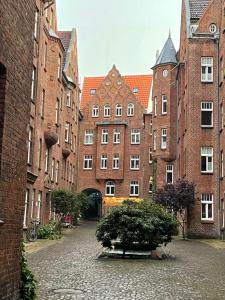 a courtyard with brick buildings and a tree in the middle at Burghofdrei hygge & zentral P-Platz Streaming in Flensburg