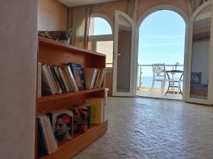 a book shelf with books and a view of the ocean at Dar diafa samira in Mirleft