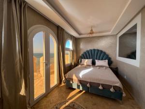 a bedroom with a bed and a large window at Dar diafa samira in Mirleft