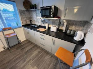 a kitchen with a black counter and a microwave at Cosy private accommodation in Corsham, near Bath in Corsham
