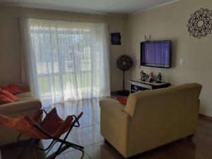 a living room with a couch and a flat screen tv at Férias Perfeitas, Praia e Piscina in Itapoa