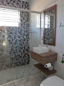 a bathroom with a shower with a sink and a mirror at Férias Perfeitas, Praia e Piscina in Itapoa