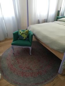 ein Schlafzimmer mit einem Bett und einem grünen Stuhl in der Unterkunft Giorgia's House in Bari