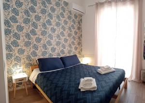 una camera da letto con un letto blu e asciugamani di Dietro il massimo a Palermo
