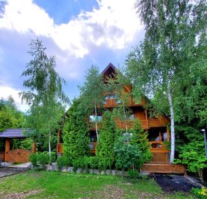 a log cabin with trees and plants around it at Gostynniy Dvir Коттеджи in Migovo