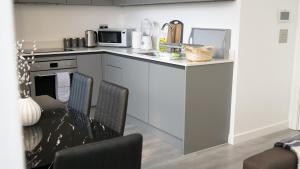 a kitchen with a counter with two chairs and a microwave at Stylish 2 bedrooms, 2 bathrooms with workspace in Milton Keynes in Milton Keynes