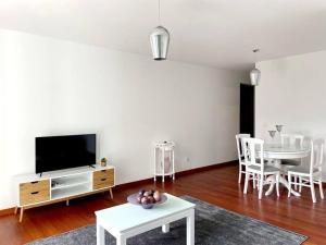 uma sala de estar com uma televisão e uma mesa e cadeiras em Ocean Pearl Apartment X no Funchal