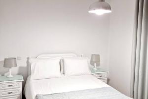 um quarto branco com uma cama branca e 2 mesas de cabeceira em Ocean Pearl Apartment X no Funchal