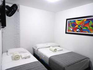 twee bedden in een kamer met een schilderij aan de muur bij aparta hotel turístico a 2 km parque del café in Montenegro