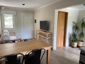 a living room with a table and chairs and a television at La Franca Aparts in Villa General Belgrano