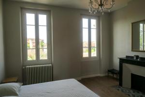 sypialnia z 2 oknami, łóżkiem i kominkiem w obiekcie Chez Carmen w mieście Albi