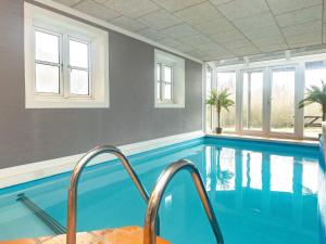 kryty basen z błękitną wodą i oknami w obiekcie 10 person holiday home in Bl vand w mieście Blåvand
