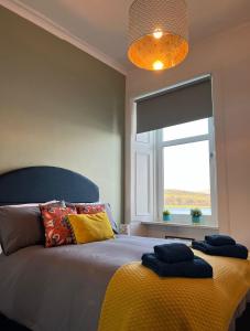 a bedroom with a bed with a yellow blanket and a window at Beautiful Upper Apartment/Stunning Sea Views, Isle of Bute in Port Bannatyne