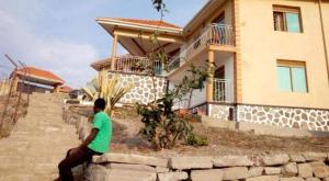een man op een muur voor een huis bij The park view lodge Queen Elizabeth N P in Kichwamba