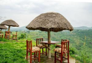 een tafel en stoelen met een grote rieten parasol bij The park view lodge Queen Elizabeth N P in Kichwamba