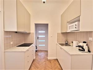 cocina con armarios blancos y encimera en J&W Apartments Świętojańska Rooms en Varsovia