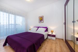 a bedroom with a bed with a purple blanket at Apartment Sara in Zadar