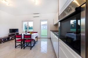 a kitchen with a table and red chairs in a room at Apartment Sara in Zadar