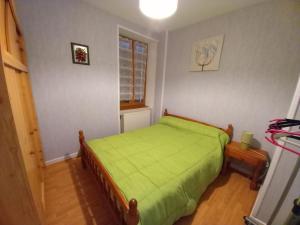 een kleine slaapkamer met een groen bed en een raam bij gite de Sauviat 25 chemin du grand Pacher le bourg de Sauviat 63120 in Sauviat