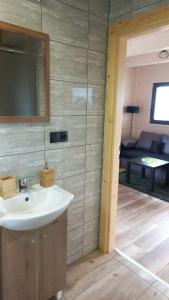 a bathroom with a sink and a room with a couch at Domek Wakacyjny Pod Gruszą in Lubin