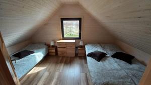 two beds in a attic room with a window at Domek Wakacyjny Pod Gruszą in Lubin