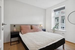a white bedroom with a large bed and a window at Central 3-bedroom apartment with a big terrace and fitness room in Aalborg